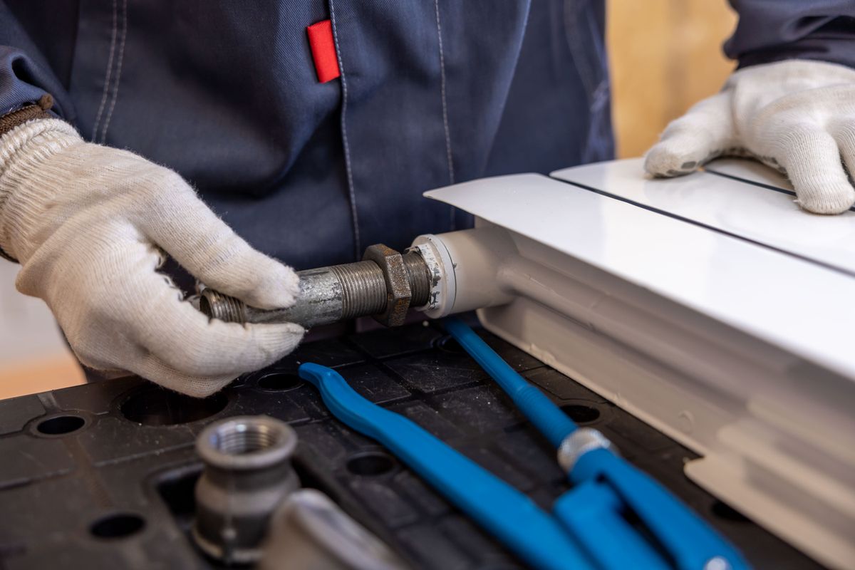 Hydraulik naprawia złącze instalacji wodnej w mieszkaniu